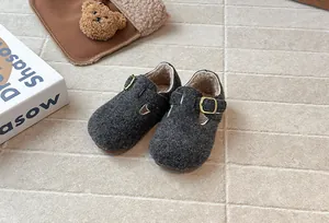 Nahaufnahme von grauen Kinder-Filzpantoletten mit warmem Fleecefutter und Schnalle.