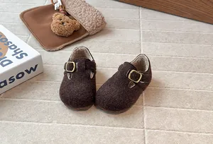 Nahaufnahme von retro braunen Filz-Kinderschuhen mit warmem Fleecefutter und Messingschnallen.