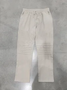Dettaglio di pantaloni in lino beige con elastico in vita e pieghe sulle ginocchia