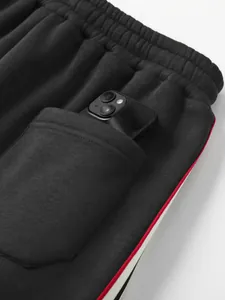 Nahaufnahme einer tiefen Seitentasche einer schwarzen gestreiften Jogginghose mit Handy.