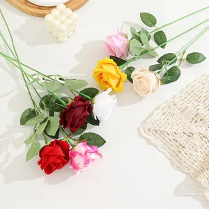 Close-up detail of artificial velvet roses in assorted colors with green leaves for flower decor.