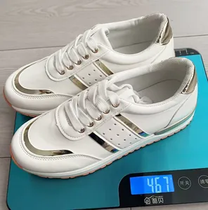 Sneakers casual bianche da donna con finiture dorate pesate su una bilancia digitale