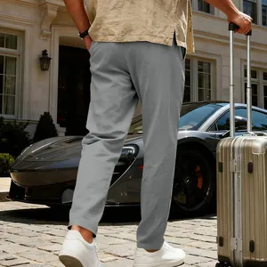 Vista posteriore di pantaloni casual in lino grigio da uomo con valigia all'aperto