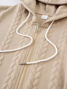 Detailed macro shot of beige jacquard textured zip-up hoodie with white drawstrings