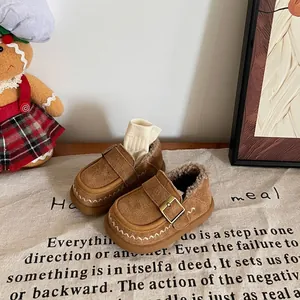 Close-up of children's brown suede moccasins with warm fleece lining and buckle detail.