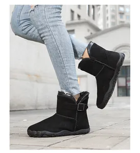 Close-up side view of women's black suede mid-calf snow boots on a model outdoors.