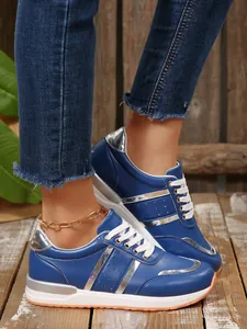 Dettaglio di sneaker con zeppa blu e argento da donna con lacci bianchi dal design moderno.