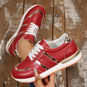 Dettaglio di sneaker spesse rosso e oro con lacci bianchi su uno sfondo di legno