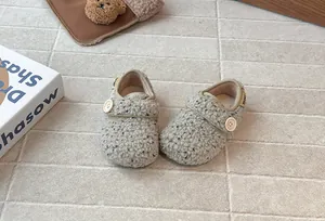 Close-up of stylish children's fleece button shoes on a minimalist tiled background.