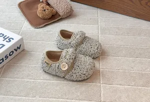 Detail view of cozy fleece kids shoes with a large button and velcro strap design.