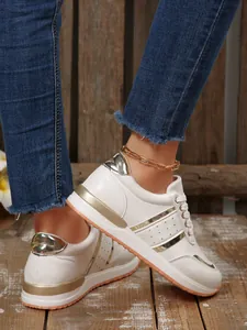 Vista dettagliata di sneaker bianche con plateau, accenti dorati e cavigliera