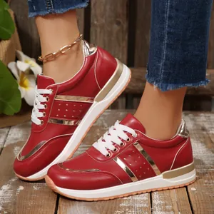 Primo piano di sneakers rosse con suola spessa, strisce dorate e dettagli di lacci bianchi.