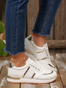 Dettaglio di sneaker platform bianche da donna con inserti metallizzati oro e lacci.