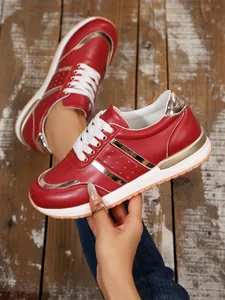 Primo piano di sneaker rosse platform con accenti dorati su sfondo di legno