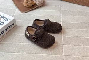Detail of cozy brown fuzzy children's shoes with button strap and warm fleece lining.