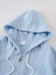 Macro detail of light blue jacquard zip-up hoodie featuring white drawstrings and hood