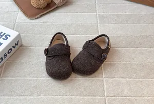 Close-up view of children's brown wool shoes featuring button detail and plush lining