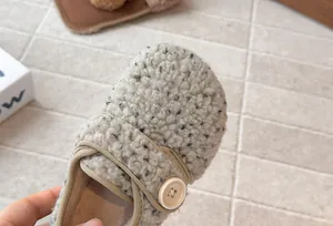 Close-up of fuzzy fleece texture and elegant button detail on girls French winter shoe.