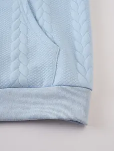 Close-up detail of light blue men's jacquard hoodie with ribbed hem and pocket