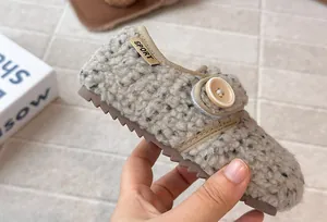 Detailed close-up of a cozy oatmeal faux fur children's shoe with a decorative button