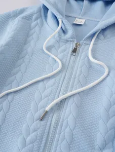 Detailed close-up of light blue cable knit hoodie featuring zipper and white drawstrings