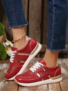 Dettaglio ravvicinato di sneaker rosse e oro da donna con suole spesse e lacci bianchi