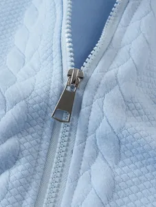Detailed close-up of light blue jacquard fabric hoodie with smooth silver metal zipper