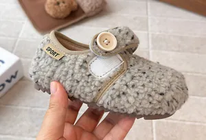 Detailed macro view of cozy fuzzy toddler girl shoe featuring decorative button and soft fur.