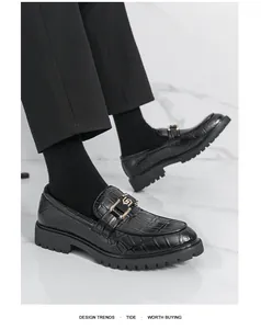 Détail en gros plan de mocassins noirs pour hommes avec texture croco et boucle d'or.