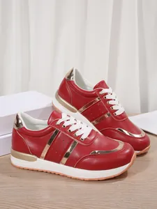 Sneakers rosse da donna con finiture dorate metallizzate e spessa suola bianca.
