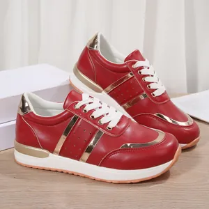 Primo piano di sneakers rosse da donna con accenti oro metallizzato e suola spessa.