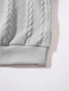 Macro detail of the grey cable knit jacquard texture and ribbed hem on casual hoodie