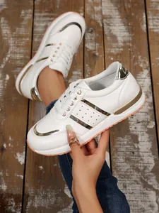 Dettaglio delle sneakers bianche con zeppa, inserti dorati e chiusura con lacci.