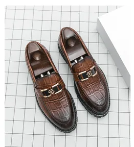 Gros plan de mocassins marron pour hommes avec texture crocodile et boucle en métal.