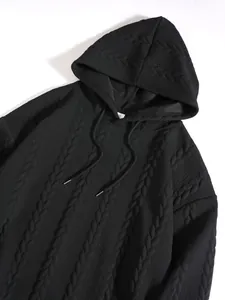 Close-up detail of a men's black hoodie with a cable-knit textured pattern and drawstrings