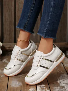 Dettaglio ravvicinato di sneakers bianche da donna con eleganti inserti dorati su legno.