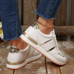 Dettaglio di sneaker bianche con accenti dorati e suole spesse con zeppa moderna