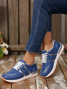 Primo piano di sneakers platform blu con strisce argento metallizzato e lacci bianchi