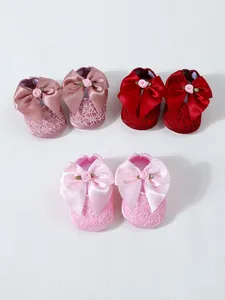Detail view of three pairs of elegant lace baby princess shoes with large satin bows