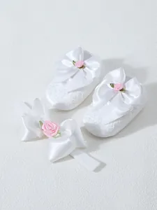 White lace infant shoes and matching floral bow headband set for girls.
