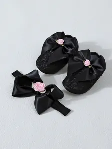 Detailed view of black baby princess shoes and matching bow headband set