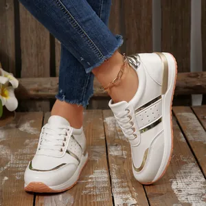 Dettaglio di sneakers bianche da donna con inserti dorati e suola spessa