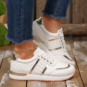 Vista laterale di sneakers bianche da donna con zeppa e raffinati accenti metallici oro