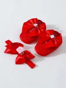 Detailed view of red lace baby shoes and matching bow headband set for 0-1 year