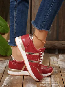 Vista dettagliata di scarpe da ginnastica rosse da donna con inserti oro e suola bianca.