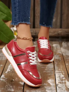 Dettaglio di eleganti sneaker rosse da donna con inserti metallici e lacci bianchi.
