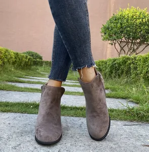 Close-up of stylish women's taupe faux suede ankle boots worn with blue denim jeans