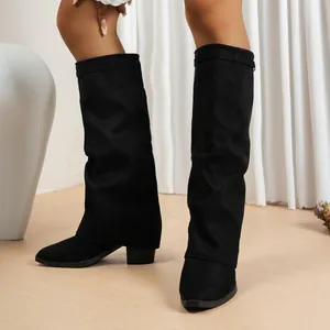 Gros plan de bottes plissées en similicuir suédé noir avec un talon bloc robuste.