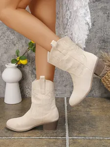 Detailed view of beige suede Western ankle boots with elegant embroidery patterns