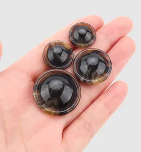 Detailed close-up of four tortoiseshell resin buttons held in a palm for size reference.